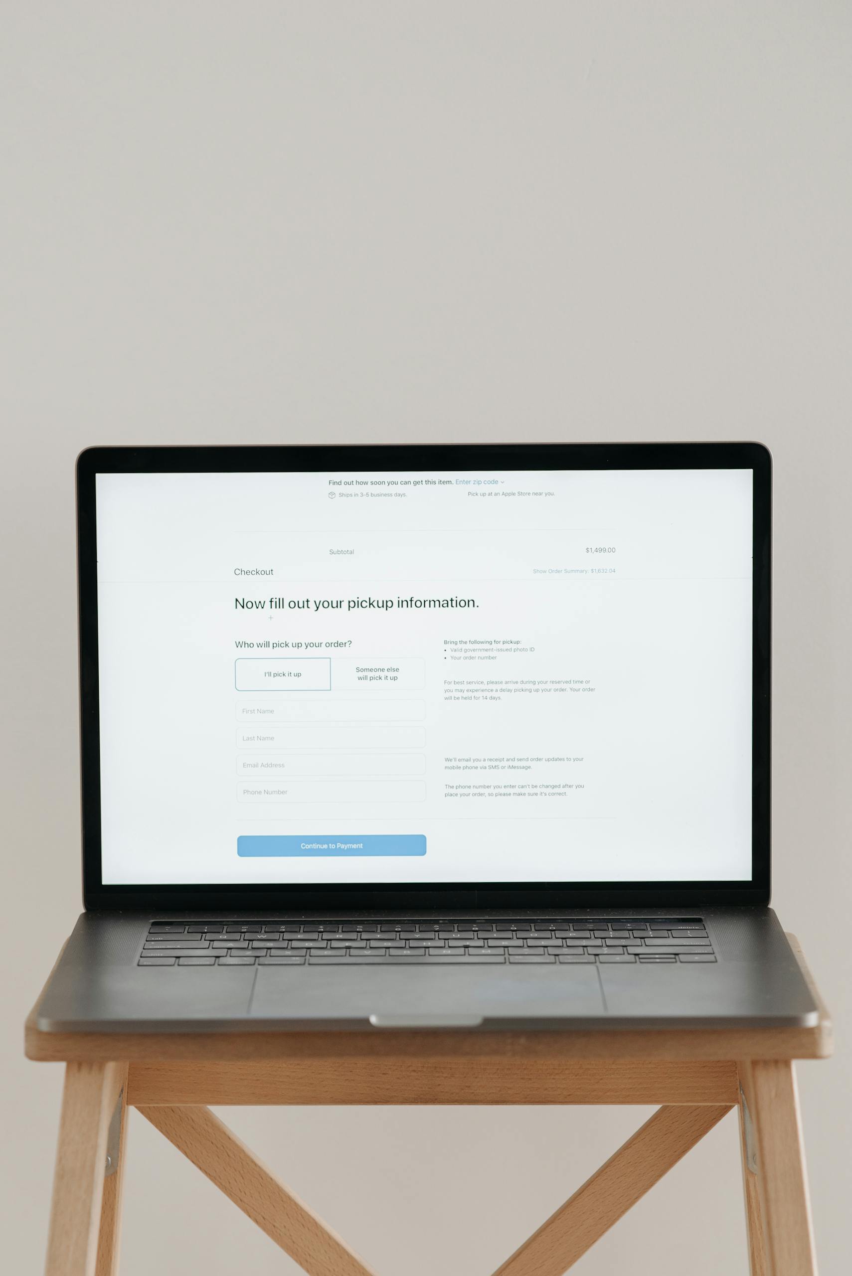 Modern laptop displaying a checkout form against a minimalist beige backdrop.